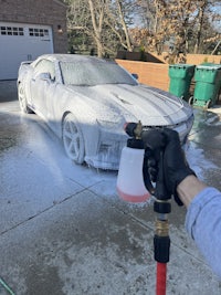 a person spraying a car with a hose